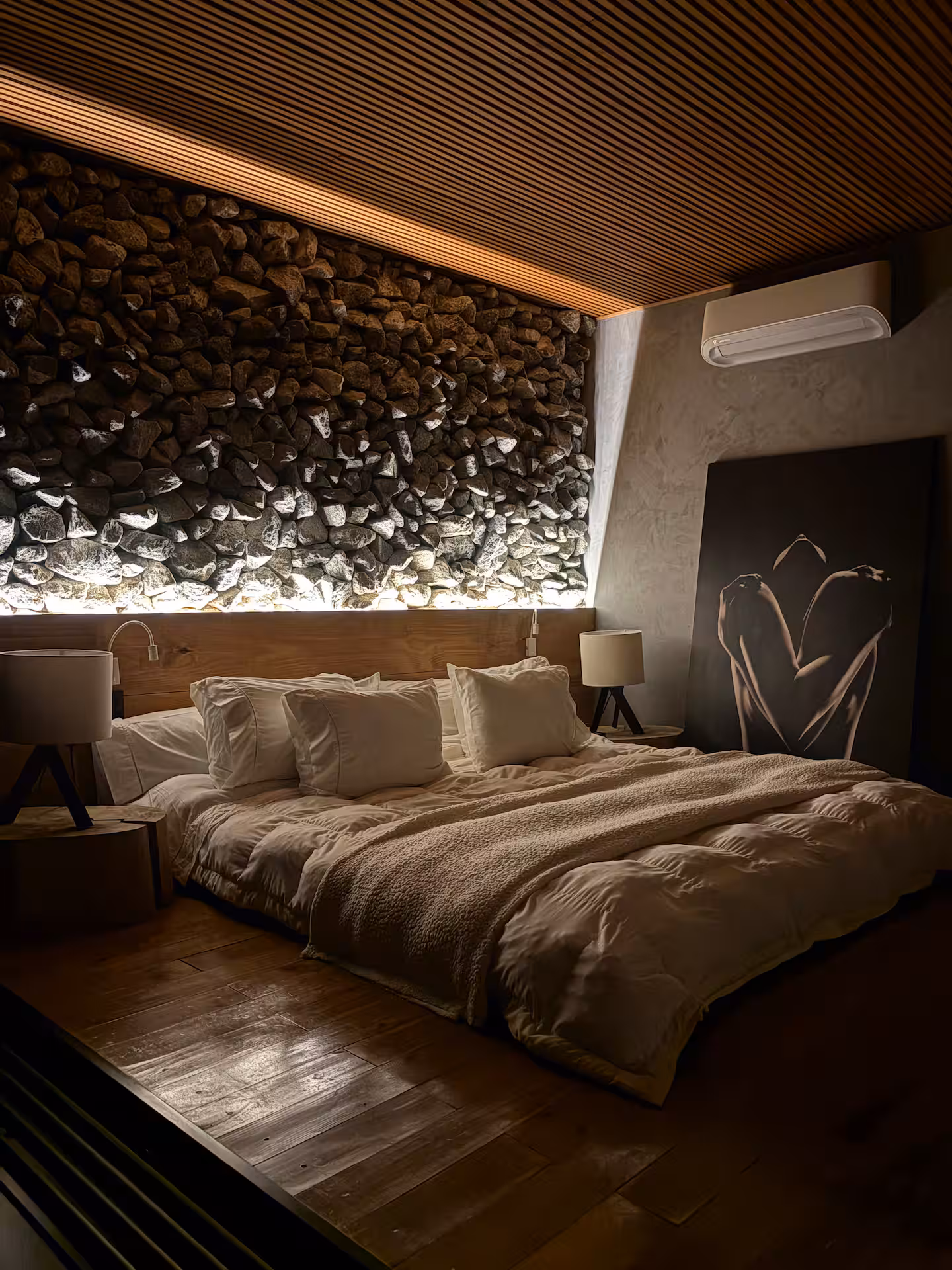 Quarto king com parede de pedra iluminada
